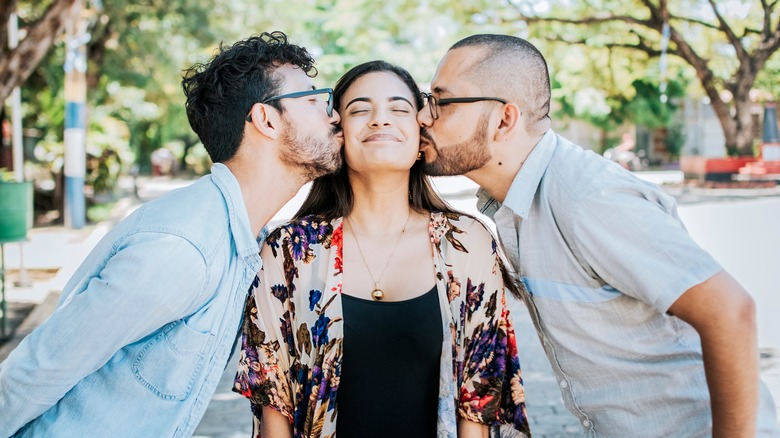 Two men kissing a woman 