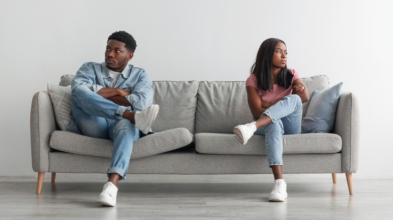 A man and a woman being stubborn on a couch