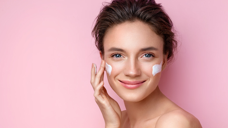 Woman applying moisturizer to her face