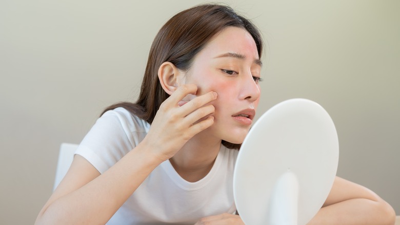 Woman looking at her skin in the mirror