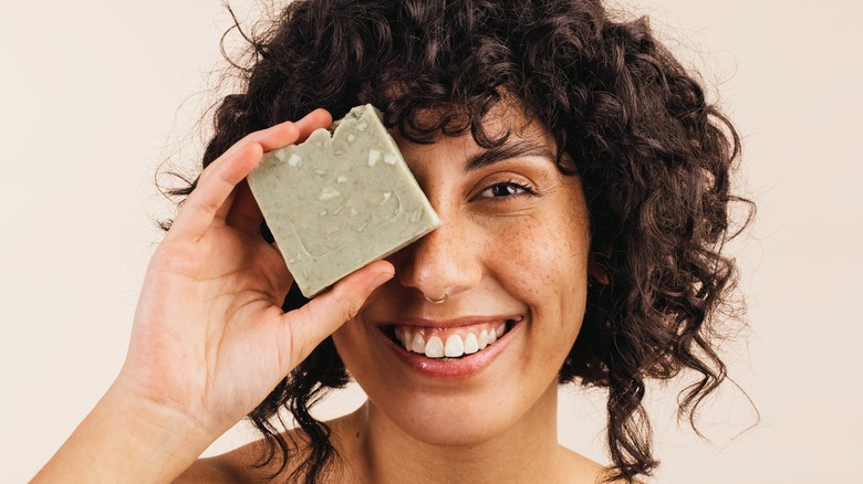Woman holding a bar of soap over her one eye