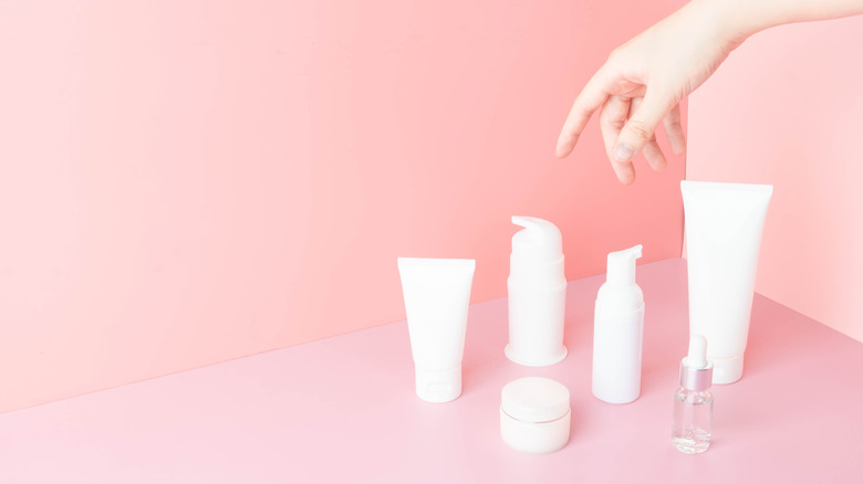 A hand reaching for different skincare products