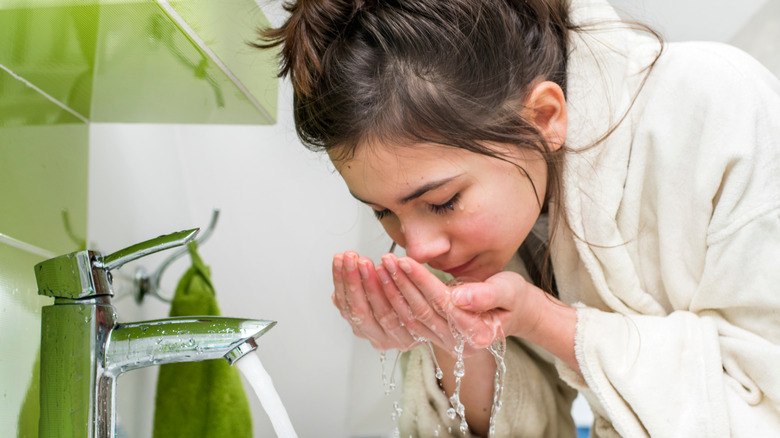 Woman washing her face at a sink