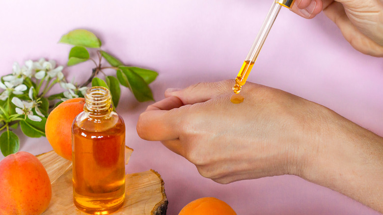 person applying apricot oil to hand