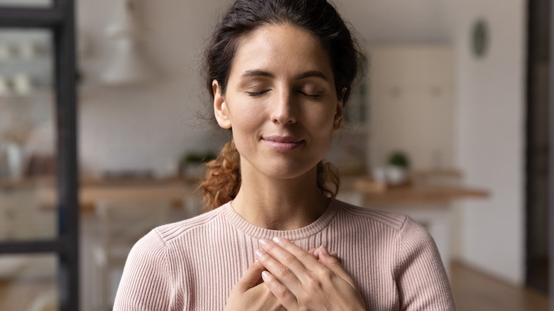 A woman looking happy with her hands place over her heart