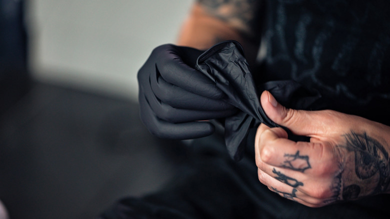 Tattoo artist taking off black gloves 