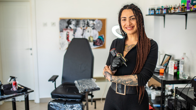 Tattoo artist smiling with tattoo gun