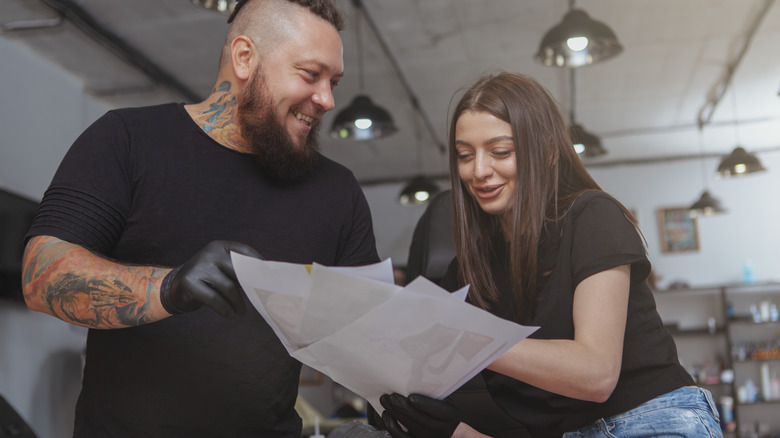 Male tattoo artist showing sketches