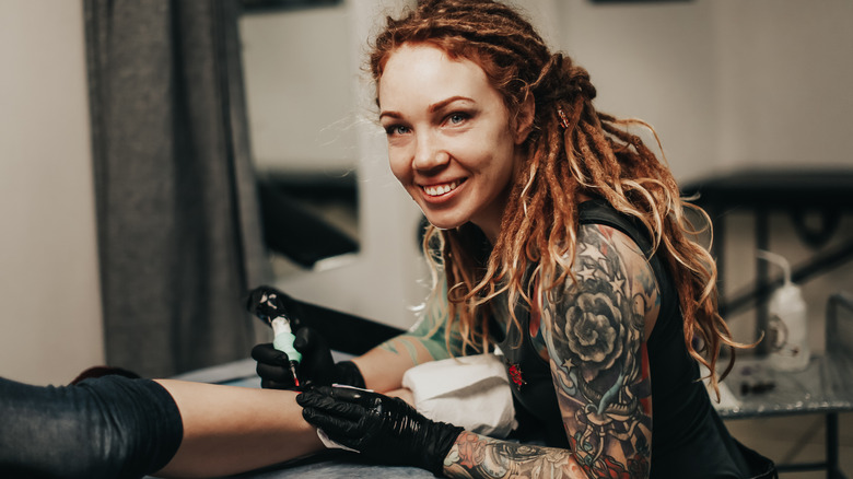 Woman with dreadlocks giving a tattoo 