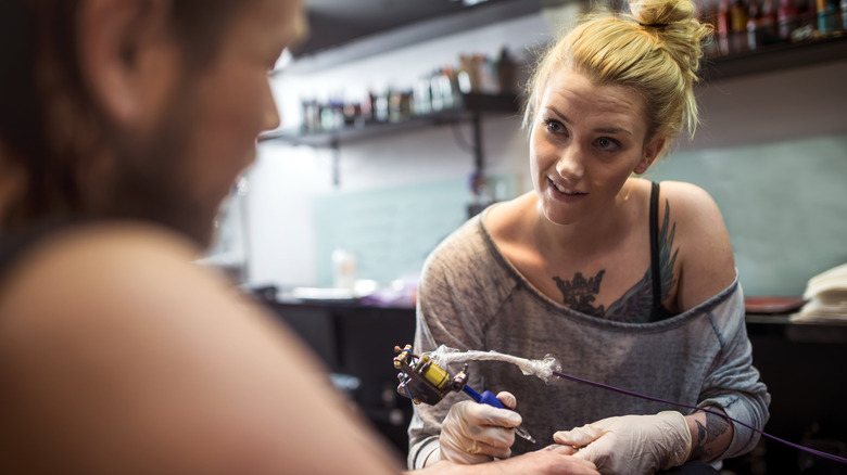 Blonde tattoo artist talking to client 