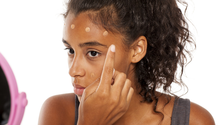 Woman applying foundation in dots to her face