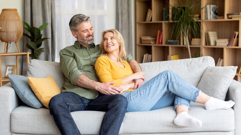 Middle aged couple cuddling on a sofa