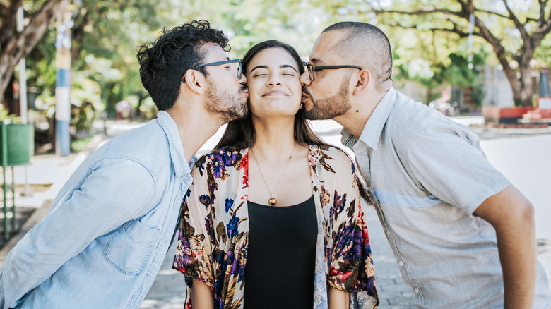 polyamorous couple kissing cheek