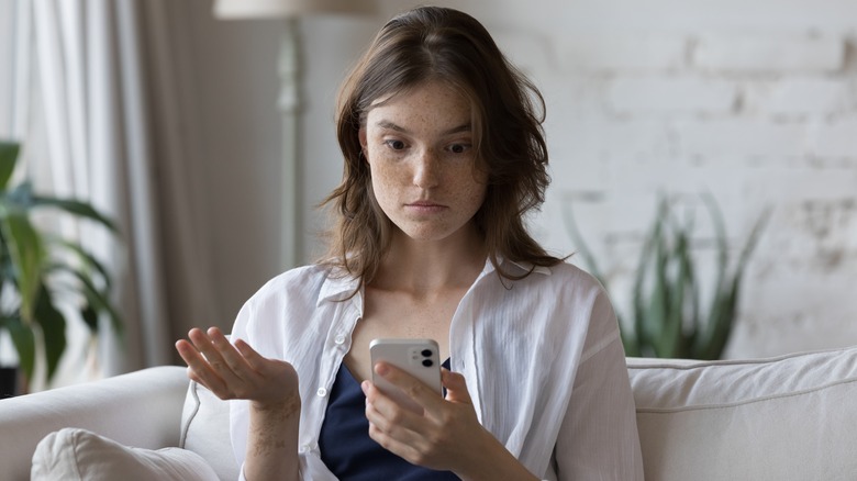 Woman looking at phone confused