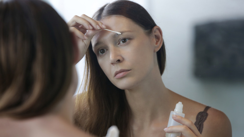 Woman applying eyebrow serum