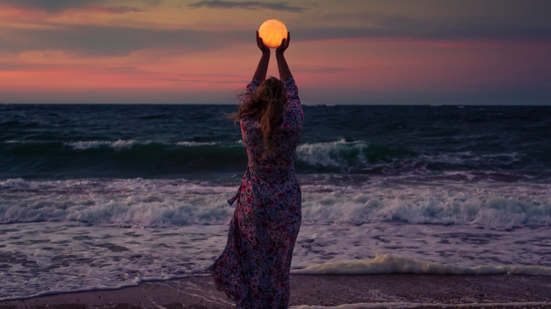 Woman posing to hold moon 