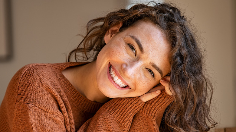 A woman with youthful-looing skin smiling 