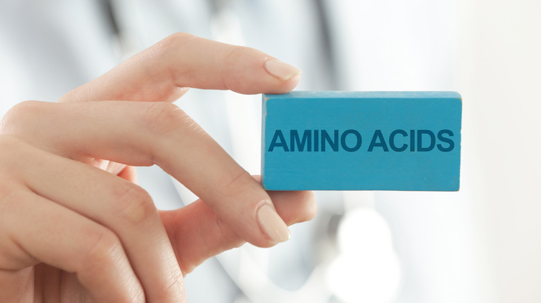 A woman holding an "Amino Acids" sign 