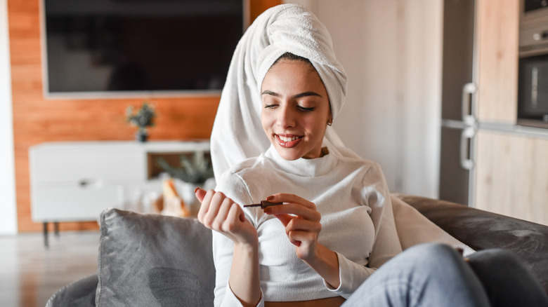 woman with hair in towel painting nails