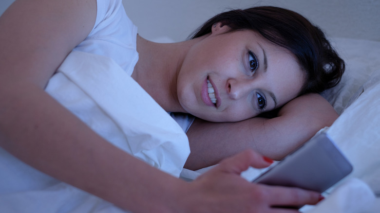 woman using smartphone in bed