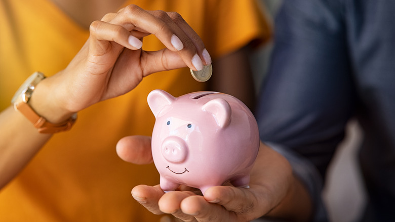 Couple putting money in piggy bank