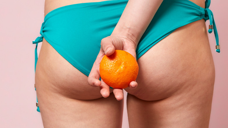 Woman with cellulite holding an orange