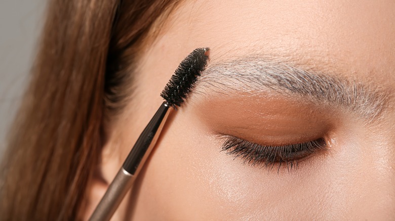 Woman with bleached eyebrows pictured with a brow brush