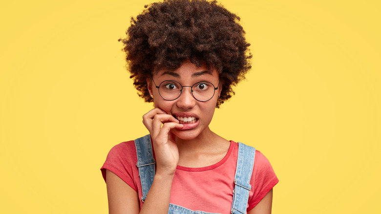 Woman biting her nails and looking nervous