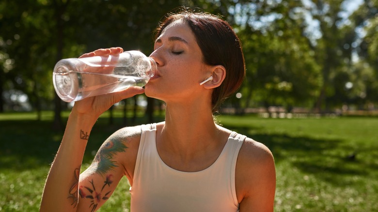 woman drinking water in park