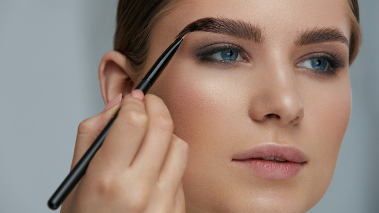 Woman applying makeup to her eyebrows
