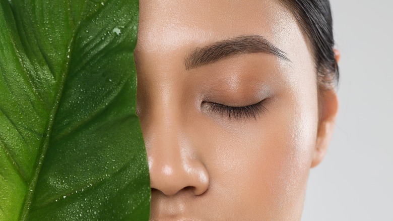 Woman with one half of her face obscured by a leaf