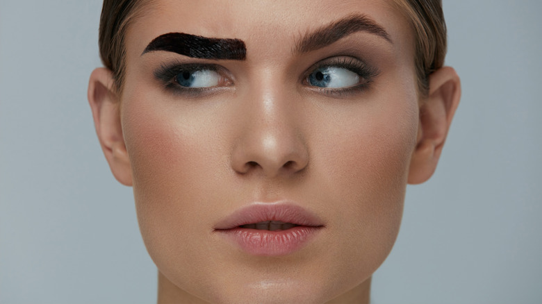 Woman with one tinted eyebrow looking suspicious