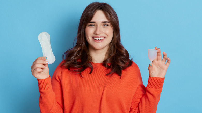 woman holding menstrual cup and pad