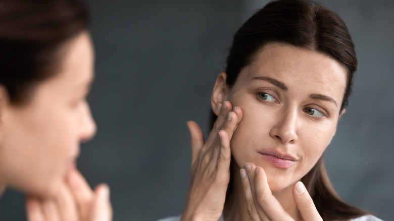 An unhappy woman looking at her irritated skin