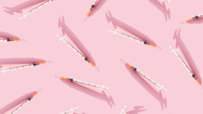 assorted syringes on pink background