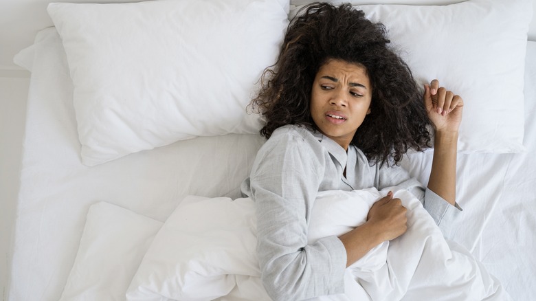 woman lying in bed and looking uncomfortable
