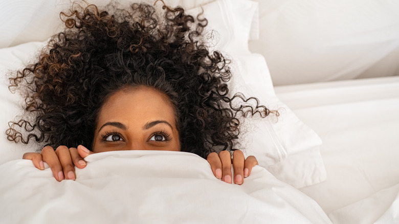 woman's face peeking out beneath a blanket