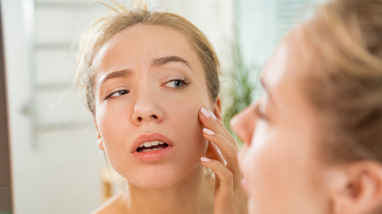 Concerned woman looking at her face