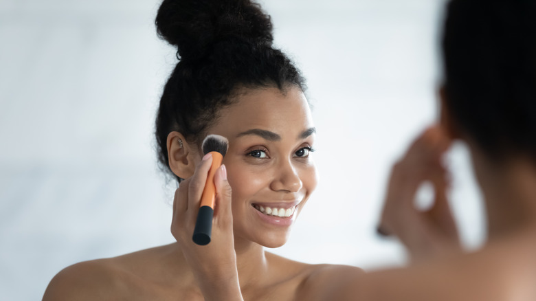 Woman applying makeup to face 