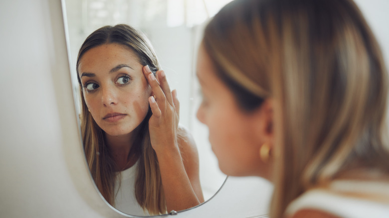 Woman looking at acne in the mirror 