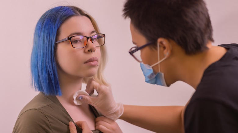 Woman getting a dermal piercing 