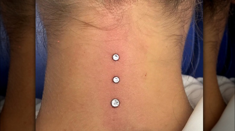 Woman with neck dermal piercings 