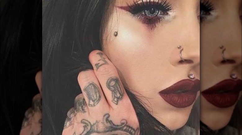 Tattooed woman dermal piercing on cheekbone 