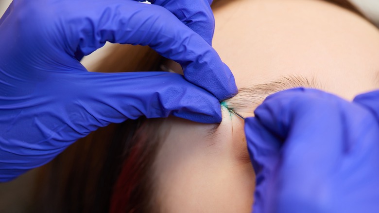 Piercer piercing an eyebrow