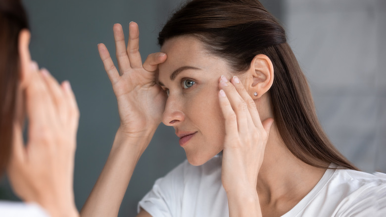 Woman studying her face in the mirror