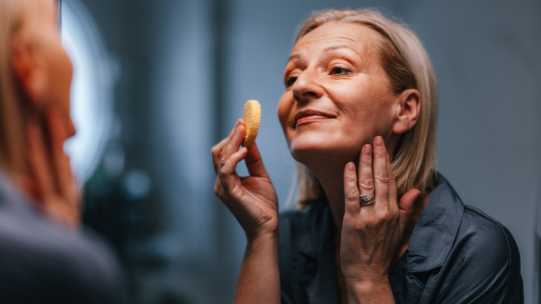 Mature woman applying powder makeup