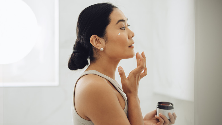 Woman applying cream to face