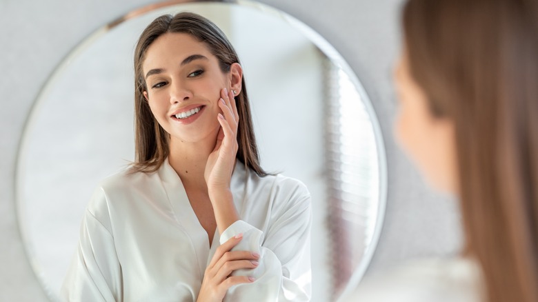 Woman admiring skin in mirror