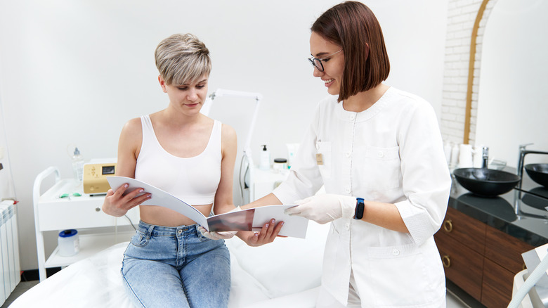 Client, cosmetologist looking at brochure