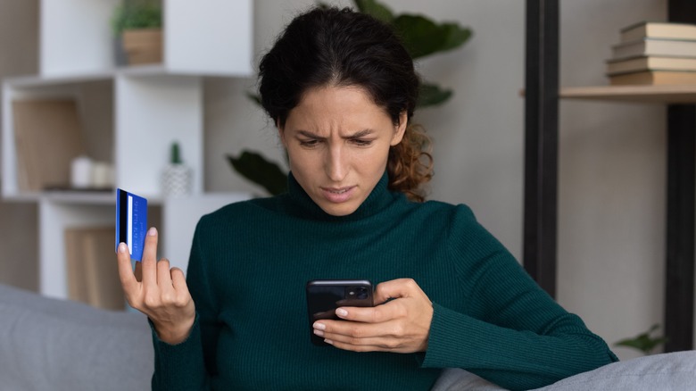 woman holding credit card in disgust